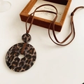 Detail eines runden Harzanhängers mit Leopardenmuster und braunem Velourslederband - Braun