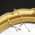 Elegant gold pearl bracelet featuring a crystal butterfly pendant on a vintage mirror - Butterfly Bracelet