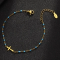 Bracciale in acciaio dorato con perline blu e ciondolo a croce su sfondo nero scuro - Oro-Blu Lago