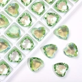 Macro detail of 12mm heart-shaped green crystal rhinestones in a white sorting tray - Fruit Green Coated