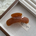 Close-up of a glossy amber hair claw clip inside a wooden box with linen fabric - Fruit Coffee