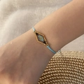 Nahaufnahme eines gewebten Boho-Perlenarmbands in Gold und Blau am Handgelenk - Seeblau #4