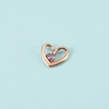 Détail du pendentif cœur en or rose avec pierre précieuse violette sur fond bleu clair - Or Rose Février
