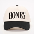 Dettaglio del ricamo HONEY su un cappello bicolore beige e nero con visiera - Taglia unica / Crema/Nero