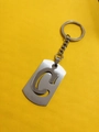 Hollow-out letter C keychain in matte metal finish on a vibrant yellow background - Letter C