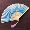 Detail of silk folding fan with blue gradient cherry blossoms and pink tassel - Blue Falling Cherry Blossoms