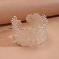 Dettaglio macro del motivo floreale traforato argento su un ampio bracciale aperto - Argento