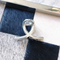 Detail view of silver metallic hair claw clip with sleek streamlined design on a patterned tray - Cross Streamline Style (9)