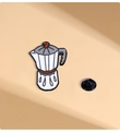 Detalle de un pin esmaltado con forma de cafetera moka blanca y marrón con cierre negro - Cafetera Moka