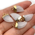 Handheld view of five crescent-shaped white natural stone pendants with gold metal caps - 10x20mm / White Jade