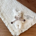 Nahaufnahme einer handgestrickten Hasenbrosche mit Spitze und brauner Schleifenverzierung - Weißer Hasenstil