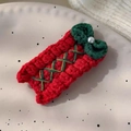 Detail of red knitted Christmas hair clip with green bow and pearl accent on a plate - 26228F Red Square Bow BB Hair Clip