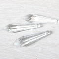 Macro view of three faceted crystal prism pendants on a light wood surface texture - Pointed Cone Transparent (38mm)