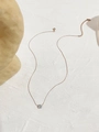 Detalle de un collar minimalista de titanio dorado con un colgante de circón brillante - Oro rosa
