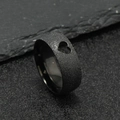Close-up of black matte stainless steel ring with laser-cut heart pattern on a dark rock - Black Hollow Heart (8mm)