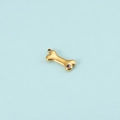 Close-up of golden dog bone pendant with purple zircon inlay for DIY jewelry design - Gold February