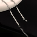 Dettaglio macro della catena a serpente in acciaio argento con motivo e chiusura a moschettone - Argento Goffrato