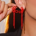 Elegant red rhinestone bow tassel earrings worn by a model in a warm studio light - Festive Party Red Bowknot