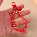 Close-up of red beaded keychain with metallic bell charm and glossy finish beads - Red
