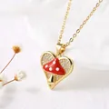 Macro detail of gold heart pendant featuring a red mushroom and micro-pave crystals - Heart Zirconia Mushroom
