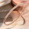 Detalle macro de un brazalete de acero de titanio oro rosa con texturas trenzadas y perlas - Oro rosa