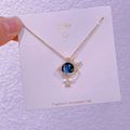 Primo piano dettagliato di una collana dorata cielo stellato con ciondoli luna e pianeta blu - Luna Stella Pianeta (XK0020)