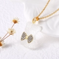 Détail d'un collier plaqué or avec un pendentif ours blanc translucide et un nœud doré - Transparent