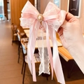Fermaglio per capelli rosa per bambine con pizzo e perla tenuto in mano - Molletta con Nastri / Rosa Chiaro