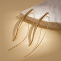Detailed view of long gold teardrop hook earrings on marble texture background - Earring Hooks / Gold