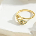 Detailaufnahme des goldenen Evil Eye Rings mit Zirkonia auf Natursteinhintergrund - Blauer Zirkonia