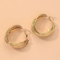 Makroaufnahme goldener gedrehter Creolen mit polierter Metallstruktur und geometrischem Design - Gold