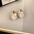 Dettaglio macro di orecchini a lobo in argento irregolari con trama in metallo martellato - Argento