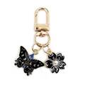 Detail of alloy butterfly and cherry blossom charms on a gold keychain - Black Butterfly + Black Cherry Blossom