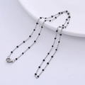 Close-up of silver-tone link necklace with black bead accents on a white edge - Steel - Black Beads