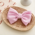 Detailed view of a textured pink fabric bow hair clip placed inside a woven basket - Pink