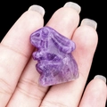 Miniature purple quartz crystal rabbit carving held on finger to show small size - Amethyst