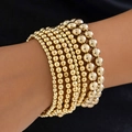 Close-up of stacked gold beaded bracelets with various sized beads on a black background - Gold Multi-layer Gradient Beaded Style (4706) / Gold