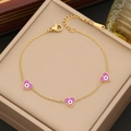 Close-up of gold chain bracelet featuring three purple enamel heart evil eye charms - Purple