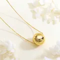 Detailed view of a polished gold spherical pendant on a delicate copper box chain - Gold Large Polished Sphere
