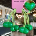 Detail of green heart resin charms and yellow elastic hair ties on pink card packaging - Green
