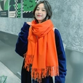 Soft orange cashmere-like wool scarf with tassel edges worn by a model in winter - Orange Red