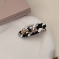Detail of marble pattern hair clip with gold butterfly accent on a ceramic tray - Black and White