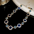 Makroansicht der silbernen Halskette mit blauen Edelsteinen und funkelndem Diamantkranz - Halskette - Gold - Blau