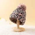 Rosafarbene Strickmütze mit Leopardenmuster und großem Pelzbommel auf einem Holzständer - M (56-58cm) / Schwarz und Rosa Leopardenmuster