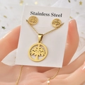Macro view of gold stainless steel tree of life necklace and stud earrings set on cards - Round Tree of Life