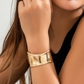 Bracciale rigido dorato minimalista a forma di V con finitura lucida sul polso della modella - Oro