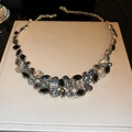 Dettaglio di collana a bavaglio con cristalli neri e blu-verdi in metallo dorato - Collana a Goccia con Strass Neri / Nero