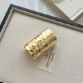Details einer goldenen Manschette mit gehämmerter Wabenstruktur auf einem Display - Gold Krokodil/Hammerschlag Muster / Gold