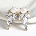 Elegant gold drop earrings with white pearls and sparkling leaf-shaped crystals on ceramic - White