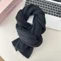 Detailed view of black knitted wool scarf featuring soft chunky cable knit texture - Black